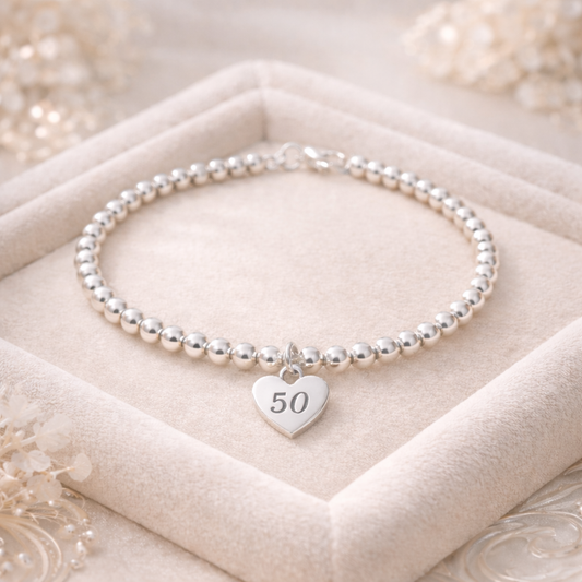 Close-up of silver 50 milestone bracelet with heart charm and lobster clasp