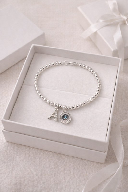Minimalist silver beaded bracelet with initial and evil eye charm