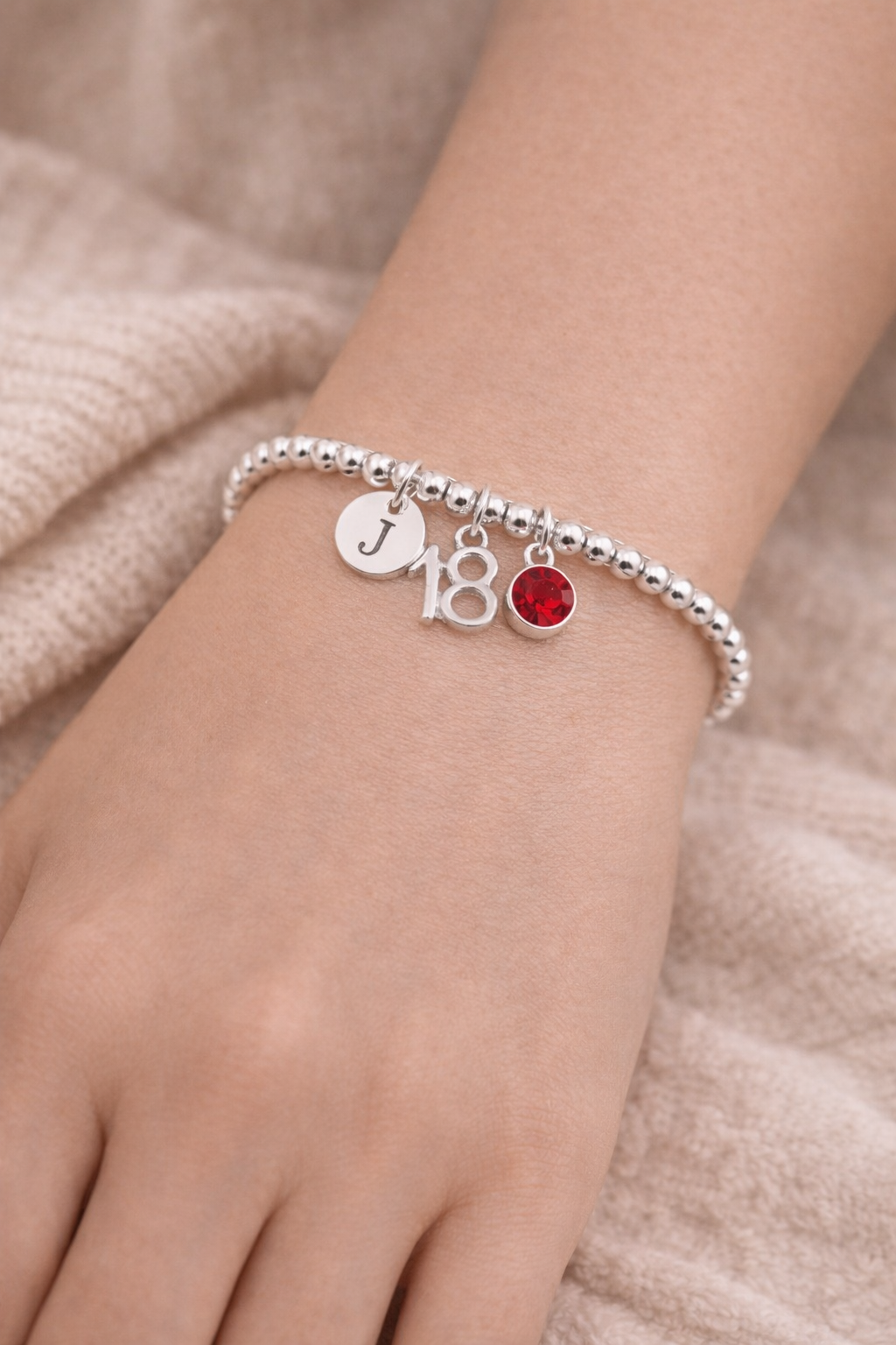 18th birthday bracelet worn on wrist with initial and birthstone charm