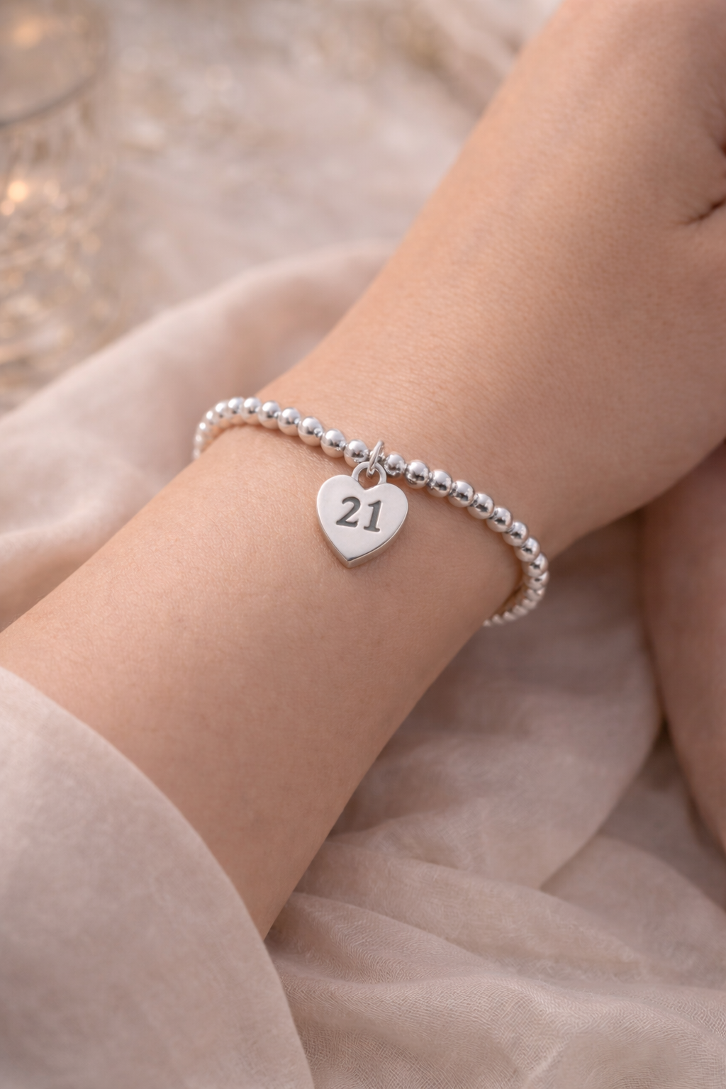 Close-up of silver bracelet with heart charm engraved 21