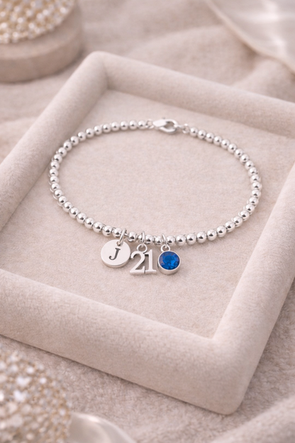 Close-up of 21 number charm and birthstone on silver beaded bracelet
