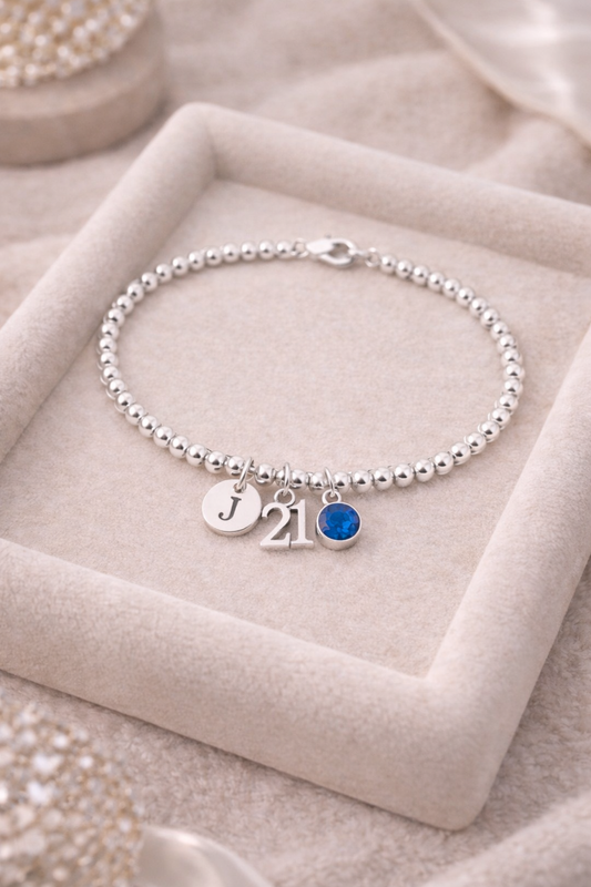 Close-up of 21 number charm and birthstone on silver beaded bracelet