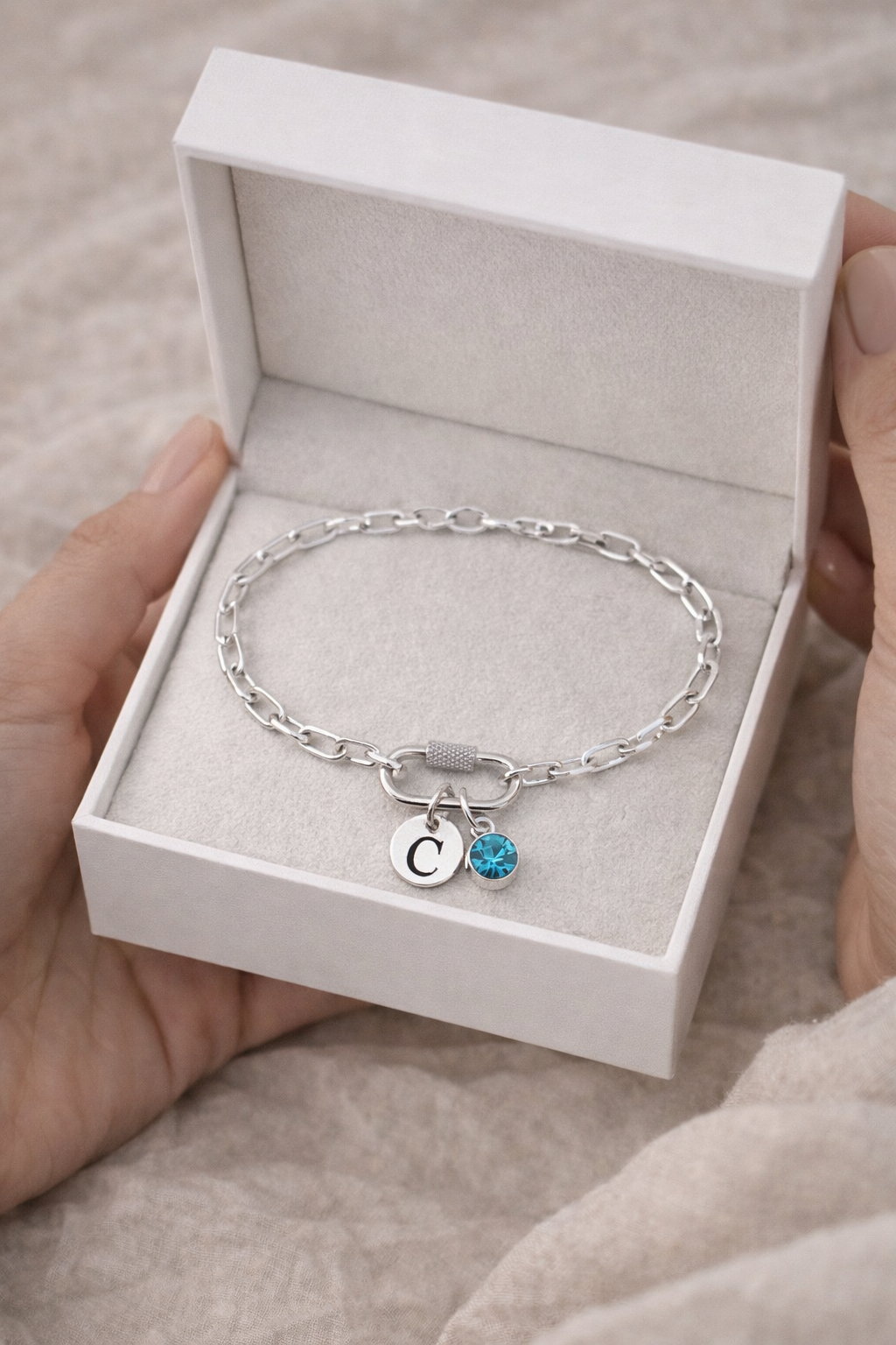 Close-up of initial letter charm and birthstone on silver chain bracelet