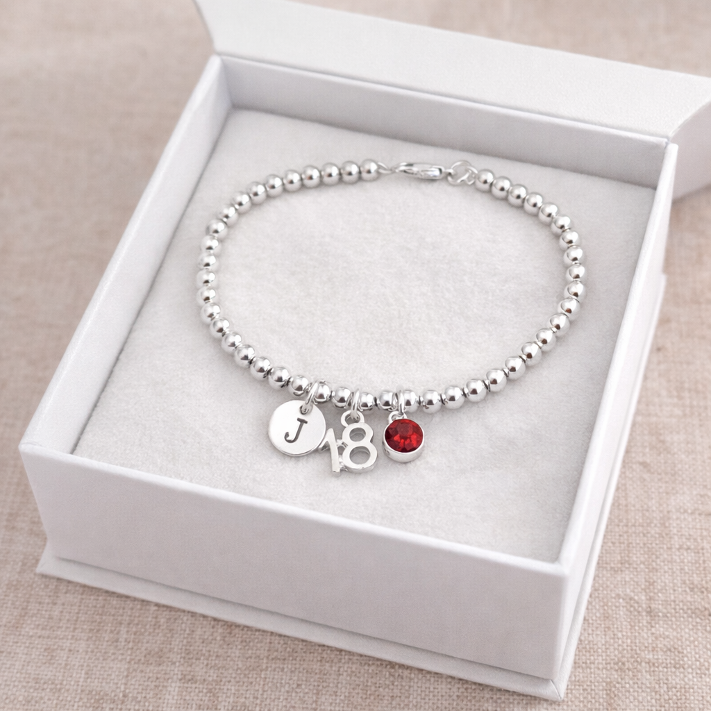 Close-up of number 18 charm and birthstone on silver bead bracelet