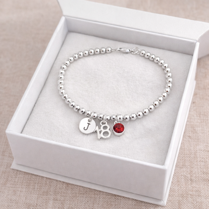 Close-up of number 18 charm and birthstone on silver bead bracelet