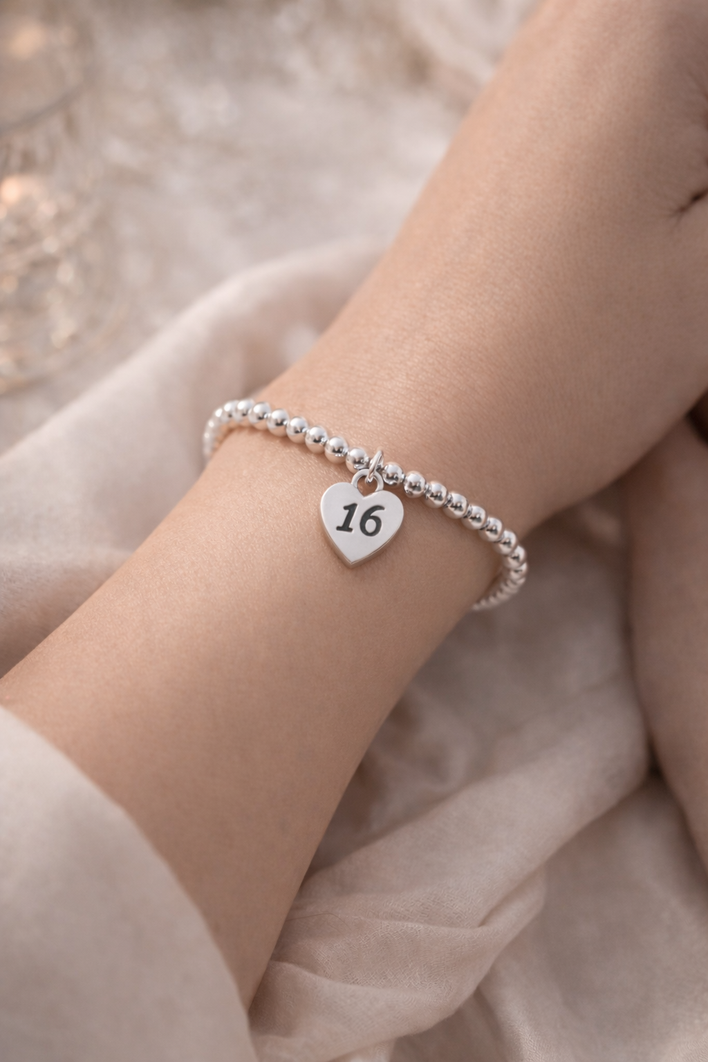 Close-up of silver bracelet with heart charm engraved 16