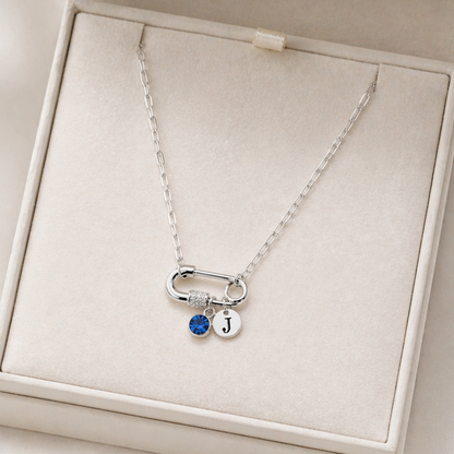 Close-up of silver carabiner necklace with initial charm and birthstone detail