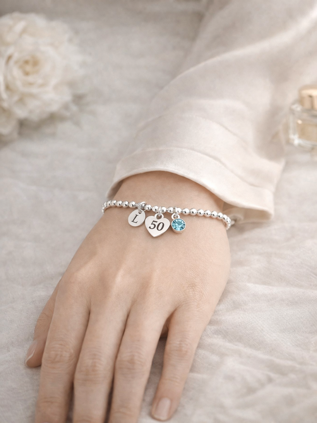 Custom silver bracelet with initial pendant and birthstone charm celebrating turning 50.
