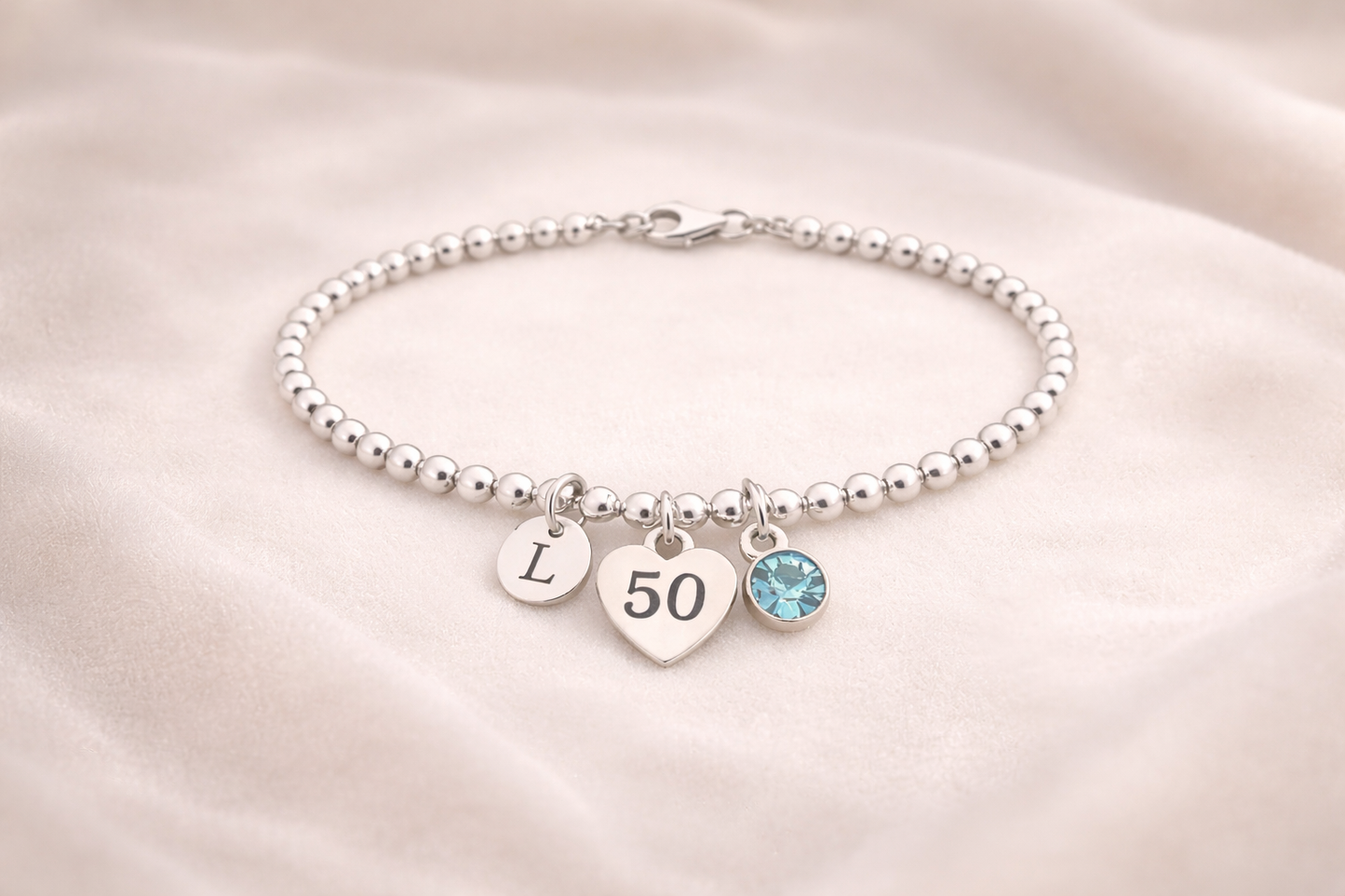 Elegant silver 50th birthday bracelet with engraved initial charm and colored birthstone