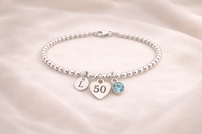 Elegant silver 50th birthday bracelet with engraved initial charm and colored birthstone