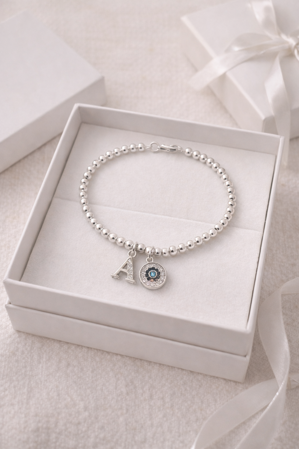 Minimalist silver beaded bracelet with initial and evil eye charm