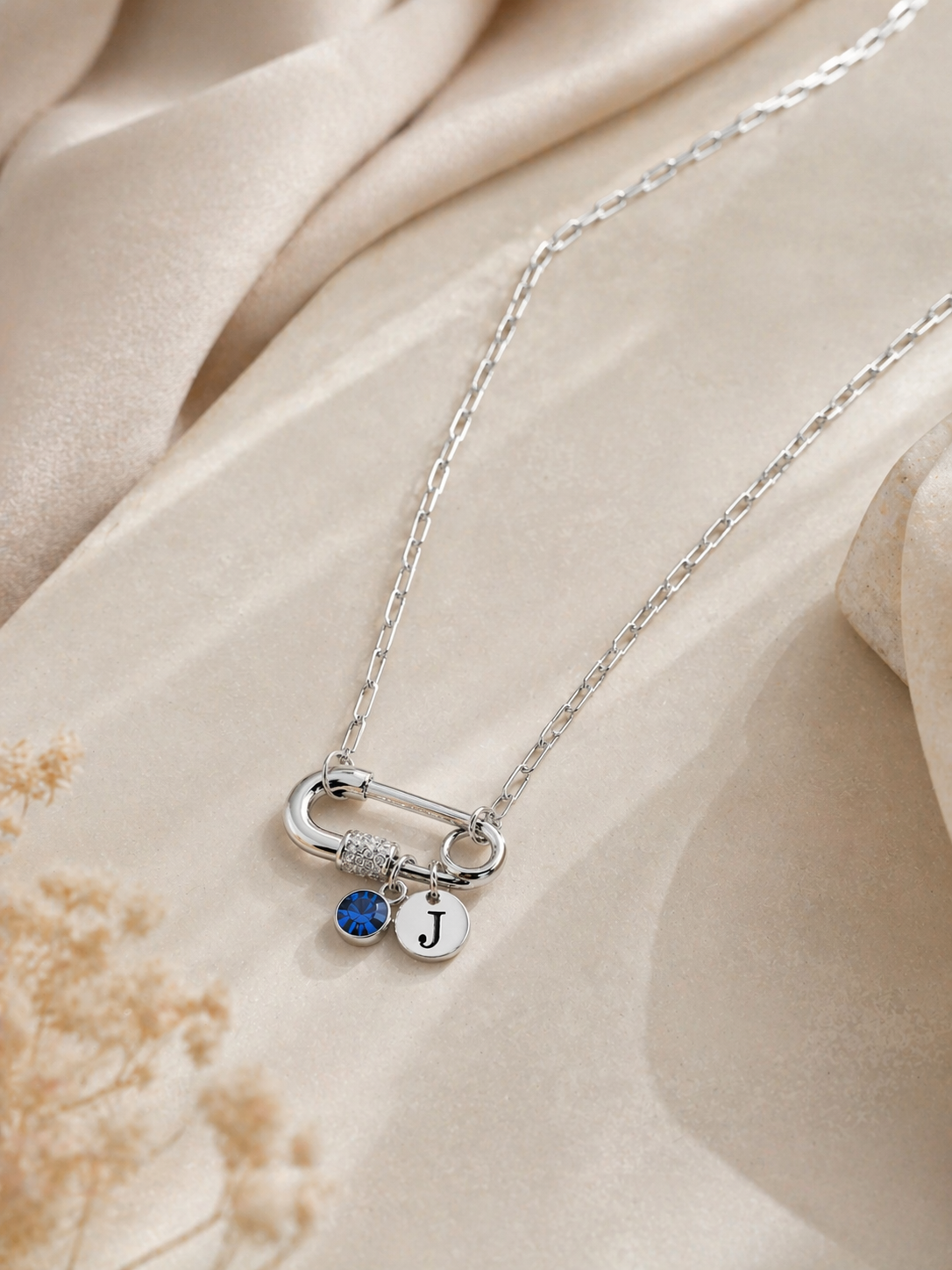 Modern silver paperclip necklace styled on soft neutral background