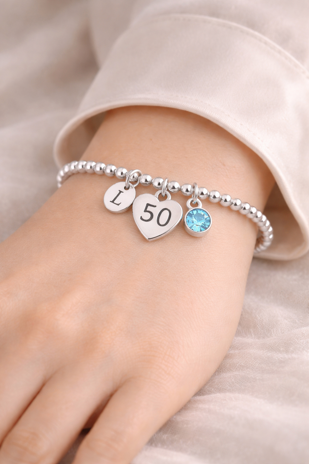 Personalized silver bracelet featuring letter initial and birthstone for 50th birthday.