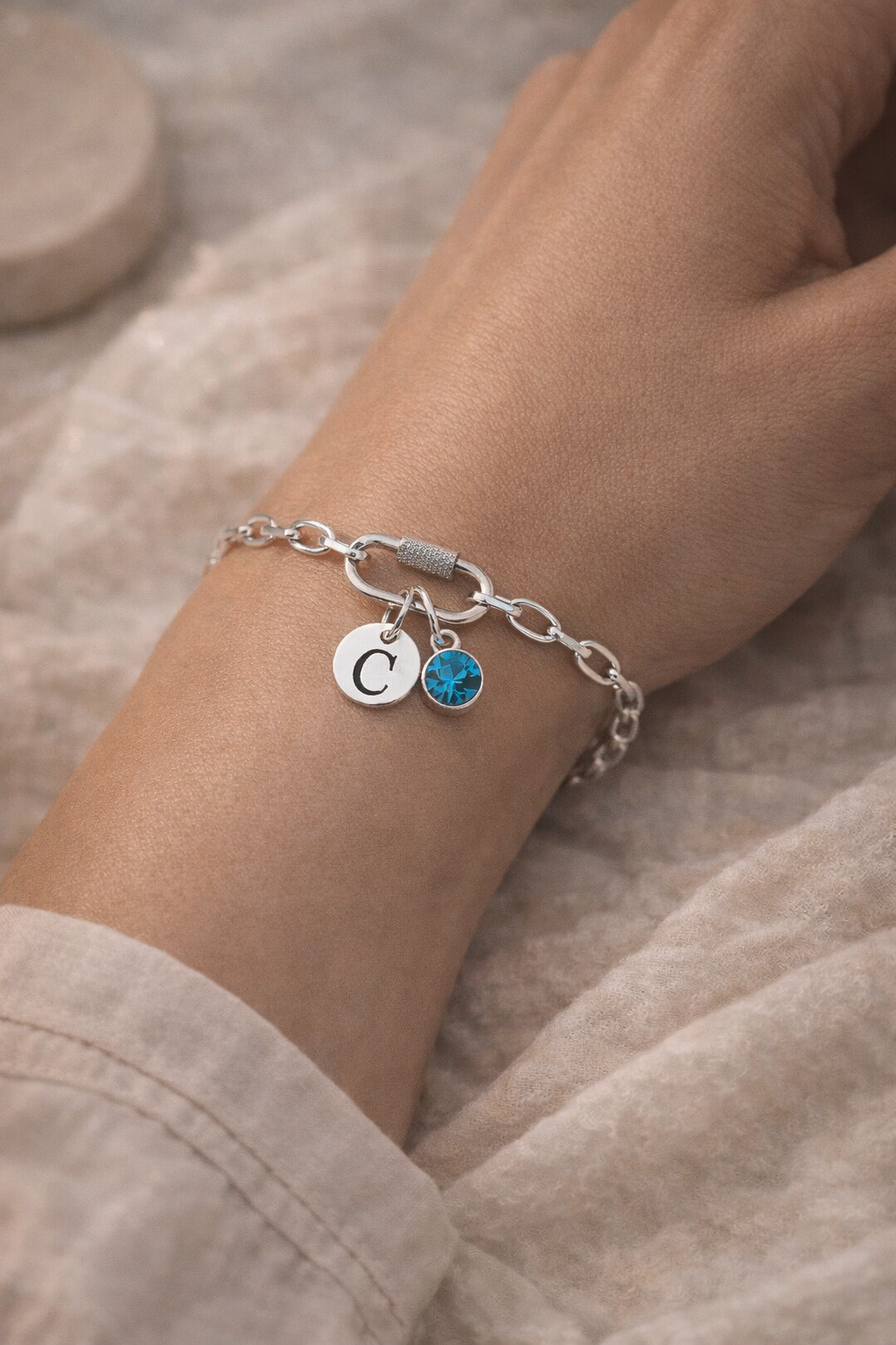 Silver-tone personalised initial and birthstone bracelet worn on wrist