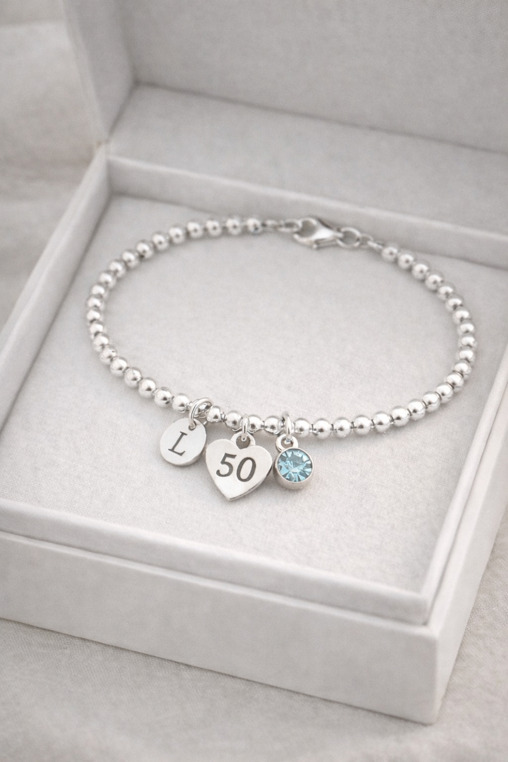 silver bracelet with initial pendant and birthstone charm celebrating turning 50.